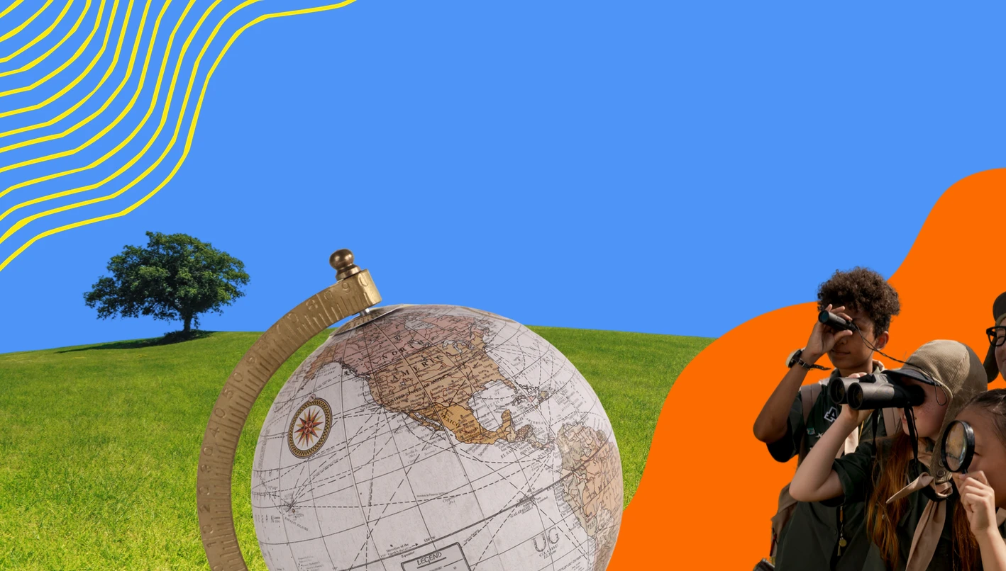 Globe on a grassy hill with children exploring through binoculars and a magnifying glass